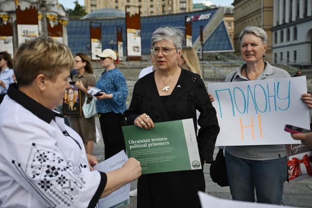Ambassador of Canada to Ukraine Natalka Cmoc (C) holds a placard during a meeting marking the International Day for the Elimination of Sexual Violence in Conflict on Independence Square in Kyiv on June 19, 2026, amid the Russian invasion of Ukraine. Several people, mostly women, took part in a demonstration on Kyiv’s central square on June 19, in support of Ukrainian civilian women imprisoned by Russian authorities. (Photo by Genya SAVILOV / AFP)