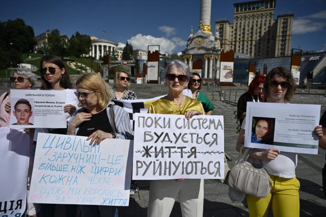 Participants hold placards reading "While the system is being built, lives are being destroyed" (R) and "Civilian women hostages are more than just numbers! Each one is waiting for us to fight for her life" (L) during a meeting marking the International Day for the Elimination of Sexual Violence in Conflict on Independence Square in Kyiv on June 19, 2026, amid the Russian invasion of Ukraine. Several people, mostly women, took part in a demonstration on Kyivs central square on June 19, in support of Ukrainian civilian women imprisoned by Russian authorities. (Photo by Genya SAVILOV / AFP)