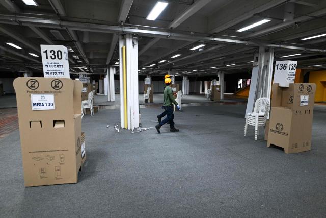 Workers walk along a hall of the Corferias polling center in Bogota,on June 19, 2026, ahead of the presidential runoff election. Colombians vote on June 21, 2026 in a presidential runoff pitting a hard-right opera-singer-turned-lawyer against a leftist senator, an election with stark consequences for the country's stumbling peace process with armed groups and strained ties with Washington. (Photo by Juan BARRETO / AFP)