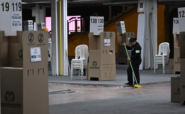 A woman cleans a hall of the Corferias polling center in Bogota,on June 19, 2026, ahead of the presidential runoff election. Colombians vote on June 21, 2026 in a presidential runoff pitting a hard-right opera-singer-turned-lawyer against a leftist senator, an election with stark consequences for the country's stumbling peace process with armed groups and strained ties with Washington. (Photo by Juan BARRETO / AFP)