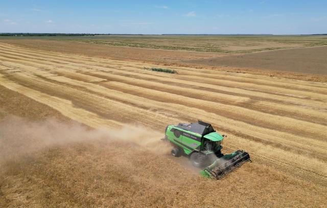 A combine harvester cuts wheat in a field near Manastirea village, southern Romania, on June 19, 2026. Romanian farmers have been forced to start the annual grain harvest weeks earlier than usual due to an intense early-summer heatwave and prolonged drought conditions driven by climate change, threatening crop yields across the region. (Photo by Daniel MIHAILESCU / AFP)