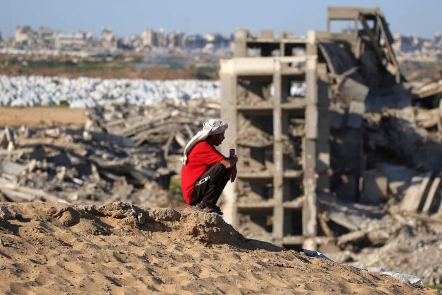 A man sits atop a hill near destroyed and heavily-damaged buildings at the Nuseirat camp for Palestinian refugees in the central Gaza Strip on June 19, 2026. Palestinian Islamist movement Hamas on Monday hailed a deal between the United States and Iran, expressing hope it would help put an end to violence in the Gaza Strip. Israel and Hamas trade near-daily accusations of truce violations and the Gaza Strip remains gripped by bloodshed as progress on permanently ending the war remains stalled. (Photo by Eyad Baba / AFP)