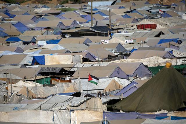 A Palestinian flag flies among shelters for people displaced by war, at the Nuseirat camp for Palestinian refugees in the central Gaza Strip on June 19, 2026. Palestinian Islamist movement Hamas on Monday hailed a deal between the United States and Iran, expressing hope it would help put an end to violence in the Gaza Strip. Israel and Hamas trade near-daily accusations of truce violations and the Gaza Strip remains gripped by bloodshed as progress on permanently ending the war remains stalled. (Photo by Eyad Baba / AFP)