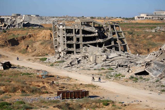 Men ride bicycles past a heavily-damaged building at the Nuseirat camp for Palestinian refugees in the central Gaza Strip on June 19, 2026. Palestinian Islamist movement Hamas on Monday hailed a deal between the United States and Iran, expressing hope it would help put an end to violence in the Gaza Strip. Israel and Hamas trade near-daily accusations of truce violations and the Gaza Strip remains gripped by bloodshed as progress on permanently ending the war remains stalled. (Photo by Eyad Baba / AFP)