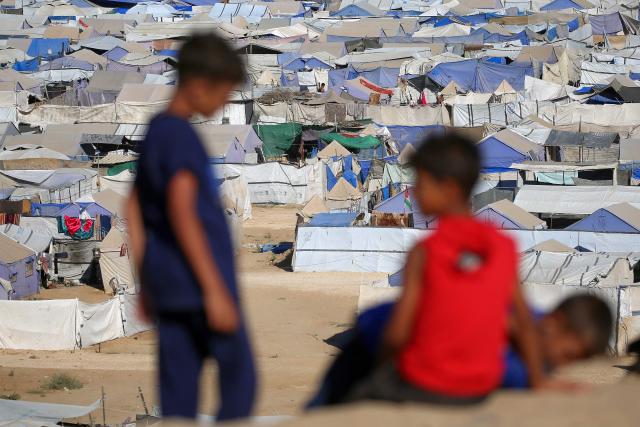 Children sit along a promontory overlooking shelters for people displaced by war, at the Nuseirat camp for Palestinian refugees in the central Gaza Strip on June 19, 2026. Palestinian Islamist movement Hamas on Monday hailed a deal between the United States and Iran, expressing hope it would help put an end to violence in the Gaza Strip. Israel and Hamas trade near-daily accusations of truce violations and the Gaza Strip remains gripped by bloodshed as progress on permanently ending the war remains stalled. (Photo by Eyad Baba / AFP)