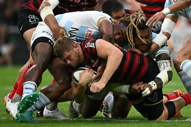 Toulouse's English flanker Jack Willis (C) is tackled by Racing 92' Fijian center Josua Tuisova (rear) Racing 92' Fijian number 8 Nathan Hughes (L) and Racing 92' French winger Gael Fickou (R) during the French Top14 rugby union semi-final match between Stade Toulousain Rugby (Toulouse) and Racing 92 at the Velodrome stadium in Marseille, southern France on June 19, 2026. (Photo by Gabriel BOUYS / AFP)