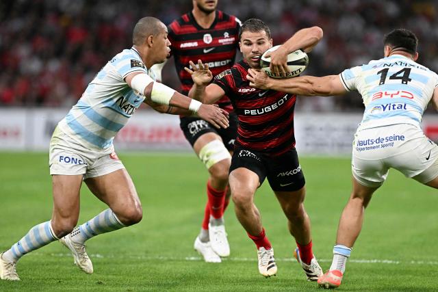 Racing 92' French winger Gael Fickou (L) and Racing 92' New Zaeland center Joseph Manu (R) attempt to tackle Toulouse's French scrum-half Antoine Dupont (C) during the French Top14 rugby union semi-final match between Stade Toulousain Rugby (Toulouse) and Racing 92 at the Velodrome stadium in Marseille, southern France on June 19, 2026. (Photo by Gabriel BOUYS / AFP)