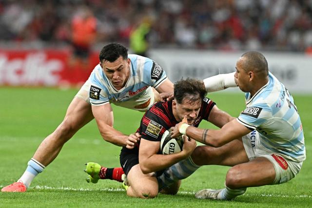 Toulouse's French centre Pierre-Louis Barassi (C) is tackled by Racing 92' New Zaeland center Joseph Manu (L) during the French Top14 rugby union semi-final match between Stade Toulousain Rugby (Toulouse) and Racing 92 at the Velodrome stadium in Marseille, southern France on June 19, 2026. (Photo by Gabriel BOUYS / AFP)