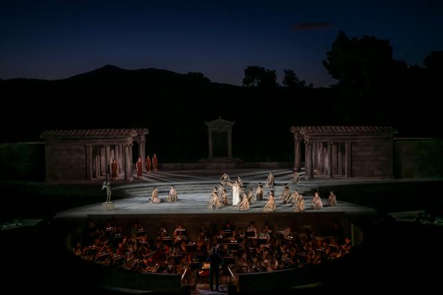Opera singers and actors perform in the opera 'Medea' at the Ancient Greek theatre of former city Epidaurus, in Nea Epidavros on June 18, 2026. With flamboyant costumes reminiscent of those from 1961, and a production reconstructed using notebooks and photographs from the period: 'Medea', the opera that brought Maria Callas her triumph, is being revived at the ancient Greek theatre of Epidaurus. During a one-off, sold-out performance on Saturday evening, the Greek National Opera returns for the first time in 65 years to this 4th-century BC amphitheatre, 200 kilometres from Athens, renowned for its exceptional acoustics. (Photo by Aris MESSINIS / AFP)