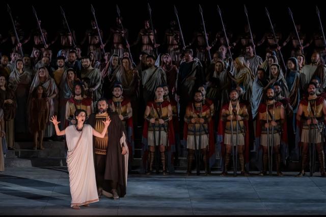 Opera singers and actors perform in the opera 'Medea' at the Ancient Greek theatre of former city Epidaurus, in Nea Epidavros on June 18, 2026. With flamboyant costumes reminiscent of those from 1961, and a production reconstructed using notebooks and photographs from the period: 'Medea', the opera that brought Maria Callas her triumph, is being revived at the ancient Greek theatre of Epidaurus. During a one-off, sold-out performance on Saturday evening, the Greek National Opera returns for the first time in 65 years to this 4th-century BC amphitheatre, 200 kilometres from Athens, renowned for its exceptional acoustics. (Photo by Aris MESSINIS / AFP)