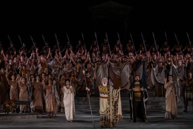 Opera singers and actors perform in the opera 'Medea' at the Ancient Greek theatre of former city Epidaurus, in Nea Epidavros on June 18, 2026. With flamboyant costumes reminiscent of those from 1961, and a production reconstructed using notebooks and photographs from the period: 'Medea', the opera that brought Maria Callas her triumph, is being revived at the ancient Greek theatre of Epidaurus. During a one-off, sold-out performance on Saturday evening, the Greek National Opera returns for the first time in 65 years to this 4th-century BC amphitheatre, 200 kilometres from Athens, renowned for its exceptional acoustics. (Photo by Aris MESSINIS / AFP)