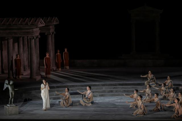Opera singers and actors perform in the opera 'Medea' at the Ancient Greek theatre of former city Epidaurus, in Nea Epidavros on June 18, 2026. With flamboyant costumes reminiscent of those from 1961, and a production reconstructed using notebooks and photographs from the period: 'Medea', the opera that brought Maria Callas her triumph, is being revived at the ancient Greek theatre of Epidaurus. During a one-off, sold-out performance on Saturday evening, the Greek National Opera returns for the first time in 65 years to this 4th-century BC amphitheatre, 200 kilometres from Athens, renowned for its exceptional acoustics. (Photo by Aris MESSINIS / AFP)