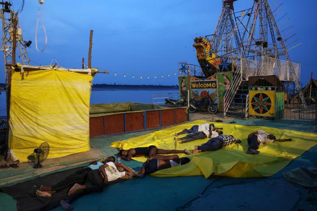 People who work with amusement rides sleep along the banks of the river Ganges amid a heatwave in Varanasi, in the early hours of June 20, 2026. (Photo by Niharika KULKARNI / AFP)