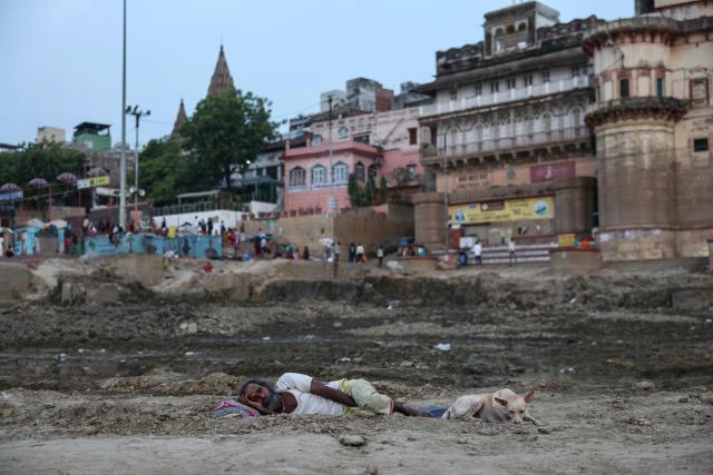 A man sleeps next to a dog along the banks of the river Ganges amid a heatwave in Varanasi, in the early hours of June 20, 2026. (Photo by Niharika KULKARNI / AFP)