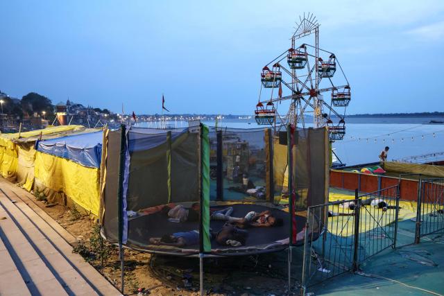 People who work with amusement rides sleep on a trampoline along the banks of the river Ganges amid a heatwave in Varanasi in the early hours of June 20, 2026. (Photo by Niharika KULKARNI / AFP)