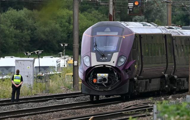 A British Transport Police officer stands on the tracks by one of two East Midlands Railway (EMR) trains that crashed into each other on June 19, 2026, south of Bedford in central England on June 20, 2026. British Transport Police said on June 20, 2026 a train driver had been killed when two trains collided north of London on June 19, in an accident that also left 11 people seriously injured. (Photo by JUSTIN TALLIS / AFP)