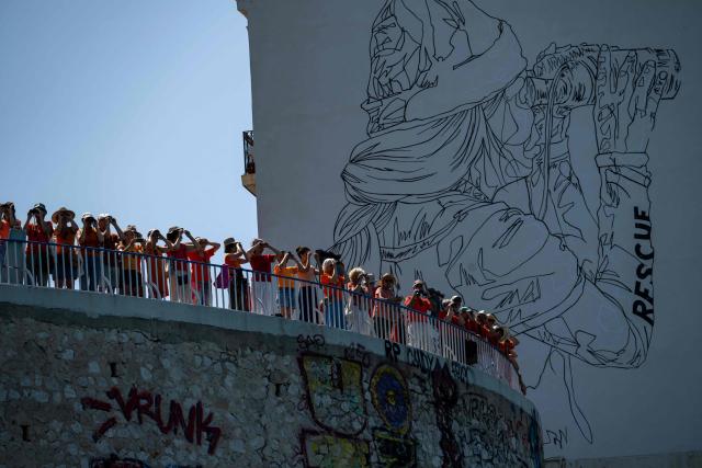 Volunteers and citizens form a human chain at the foot of the SOS MedMéditerranée mural on The Corniche Kennedy in Marseille, south-eastern France on June 20, 2026, as they express their solidarity with the organisation on its tenth anniversary. (Photo by MIGUEL MEDINA / AFP)