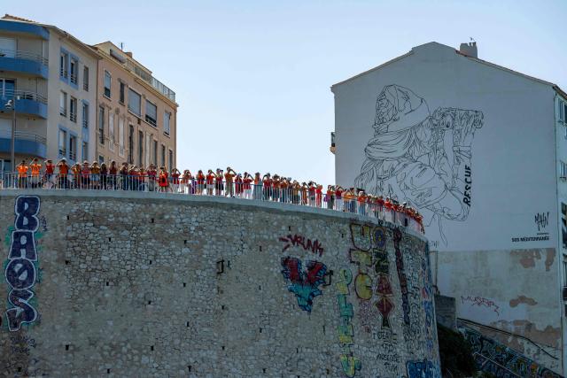 Volunteers and citizens form a human chain at the foot of the SOS MedMéditerranée mural on The Corniche Kennedy in Marseille, south-eastern France on June 20, 2026, as they express their solidarity with the organisation on its tenth anniversary. (Photo by MIGUEL MEDINA / AFP)