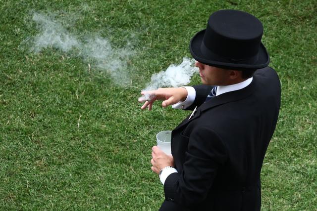 A racegoer enjoys a cigar ahead of racing on the fifth day of the Royal Ascot horse racing meeting in Ascot, west of London, on June 20, 2026. (Photo by Henry Nicholls / AFP)
