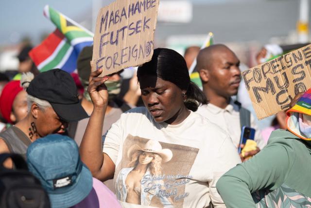 A group of about 100 people, some carrying banners and waving South African flags, take part in a march, organised by the March and March movement, protesting against illegal immigrants, in Wynberg, a Cape Town suburb, on June 20, 2026. (Photo by RODGER BOSCH / AFP)