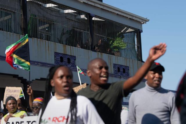 Marchers gesture towards people (not visible) they think are foreigners, as a group of about 100 people, some carrying banners and waving South African flags, take part in a march, organized by March and March, protesting against illegal immigrants, in Wynberg, a Cape Town suburb, on June 20, 2026. (Photo by RODGER BOSCH / AFP)