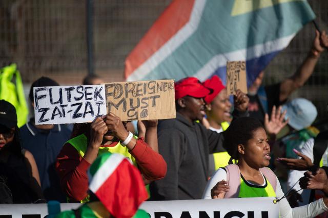 A group of about 100 people, some carrying banners and waving South African flags, take part in a march, organised by the March and March movement, protesting against illegal immigrants, in Wynberg, a Cape Town suburb, on June 20, 2026. (Photo by RODGER BOSCH / AFP)