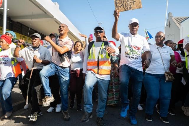 A group of about 100 people, some carrying banners, take part in a march, organised by the March and March movement, protesting against illegal immigrants, in Wynberg, a Cape Town suburb, on June 20, 2026. (Photo by RODGER BOSCH / AFP)