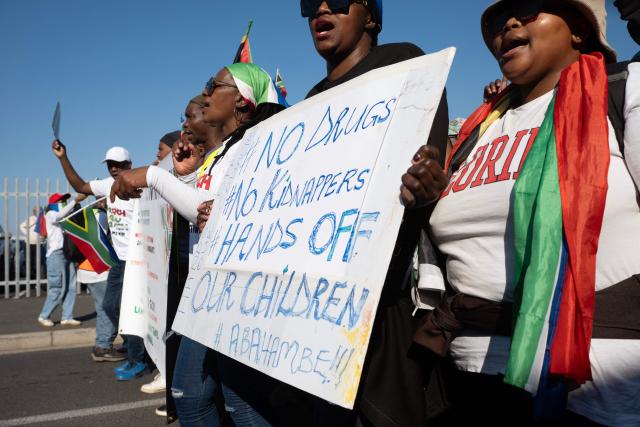 A group of about 100 people, some carrying banners and waving South African flags, take part in a march, organised by the March and March movement, protesting against illegal immigrants, in Wynberg, a Cape Town suburb, on June 20, 2026. (Photo by RODGER BOSCH / AFP)