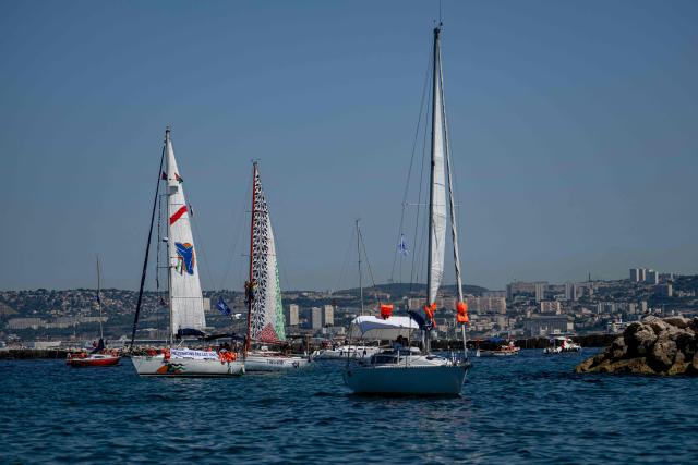 A boat with its sail in the colours of the Palestinian flag (C) is joined by other vessels in support of an action by unseen volunteers and citizens forming a human chain at the foot of the SOS Méditerranée mural on The Corniche Kennedy in Marseille, south-eastern France on June 20, 2026, as they express their solidarity with the organisation on its tenth anniversary. (Photo by MIGUEL MEDINA / AFP)