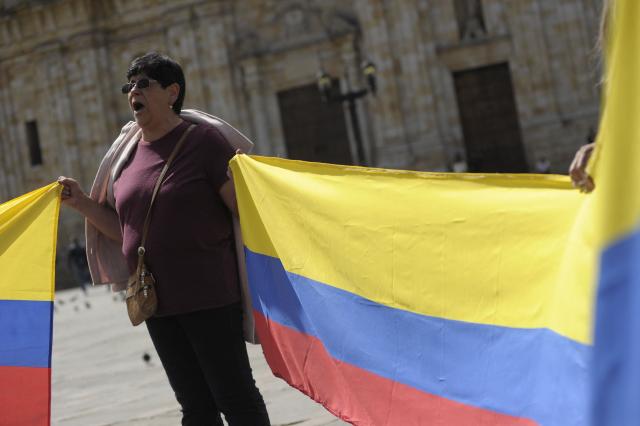 A Christian woman holds Colombian national flags as she prays for the future of the country at Murillo square in Bogota, on June 20, 2026, the day before the presidential runoff election. Colombians vote on June 21, 2026 in a presidential runoff pitting a hard-right opera-singer-turned-lawyer against a leftist senator, an election with stark consequences for the country's stumbling peace process with armed groups and strained ties with Washington. (Photo by Sebastian BARROS / AFP)