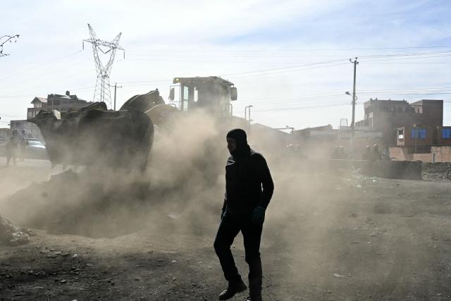 A backhoe breaks down a barricade at a blockade zone in Cruce Ventilla in El Alto, Bolivia on June 20, 2026, after Bolivian president Rodrigo Paz declared state of emergency. Bolivian President Rodrigo Paz declared a state of emergency across the Latin American country after more than six weeks of road blockades and protests demanding his resignation, saying he had exhausted "all avenues of dialogue." (Photo by AIZAR RALDES / AFP)