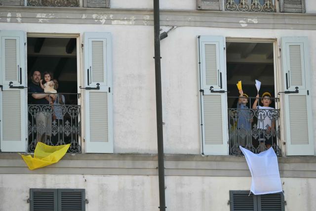 People stand at the window to see Pope Leo XIV at Piazza Duomo during a pastoral visit in Pavia on June 20, 2026. (Photo by Marco BERTORELLO / AFP)