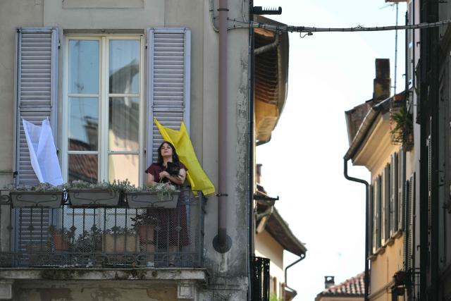 A woman stands on a balcony to see Pope Leo XIV at Piazza Duomo during a pastoral visit in Pavia on June 20, 2026. (Photo by Marco BERTORELLO / AFP)