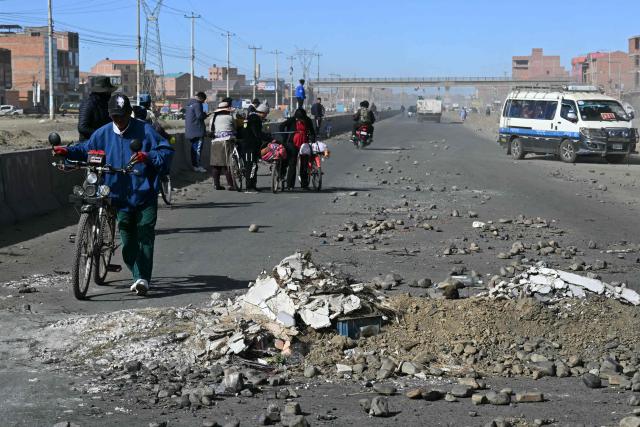 A man walks with a bicycle at a blockade zone in Cruce Ventilla in El Alto, Bolivia on June 20, 2026, after Bolivian President Rodrigo Paz declared state of emergency. Bolivian President Rodrigo Paz declared a state of emergency across the Latin American country after more than six weeks of road blockades and protests demanding his resignation, saying he had exhausted "all avenues of dialogue." (Photo by AIZAR RALDES / AFP)
