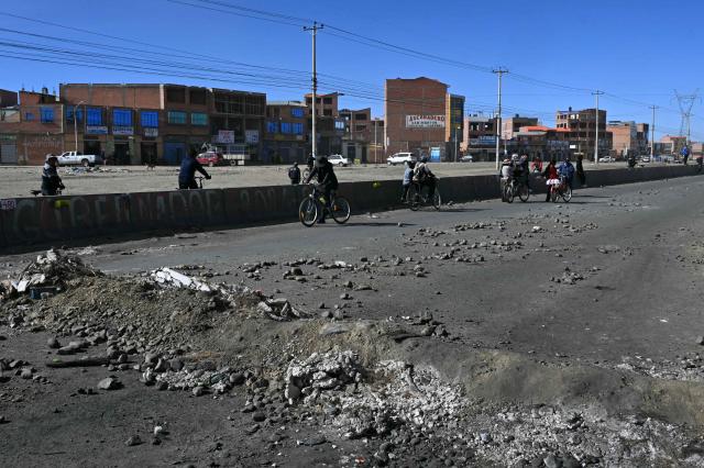 Residents ride bicycles at a blockade zone in Cruce Ventilla in El Alto, Bolivia on June 20, 2026, after Bolivian President Rodrigo Paz declared state of emergency. Bolivian President Rodrigo Paz declared a state of emergency across the Latin American country after more than six weeks of road blockades and protests demanding his resignation, saying he had exhausted "all avenues of dialogue." (Photo by AIZAR RALDES / AFP)