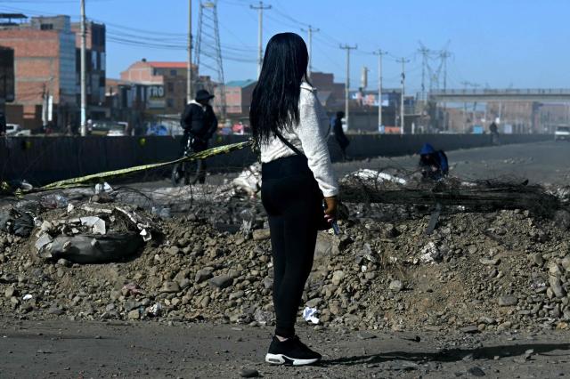 A woman looks at a barricade at a blockade zone in Cruce Ventilla in El Alto, Bolivia on June 20, 2026, after Bolivian president Rodrigo Paz declared state of emergency. Bolivian President Rodrigo Paz declared a state of emergency across the Latin American country after more than six weeks of road blockades and protests demanding his resignation, saying he had exhausted "all avenues of dialogue." (Photo by AIZAR RALDES / AFP)
