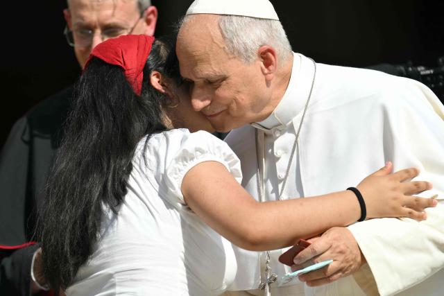 A young girl hugs Pope Leo XIV outside the cathedral during a pastoral visit in Pavia on June 20, 2026. (Photo by Marco BERTORELLO / AFP)