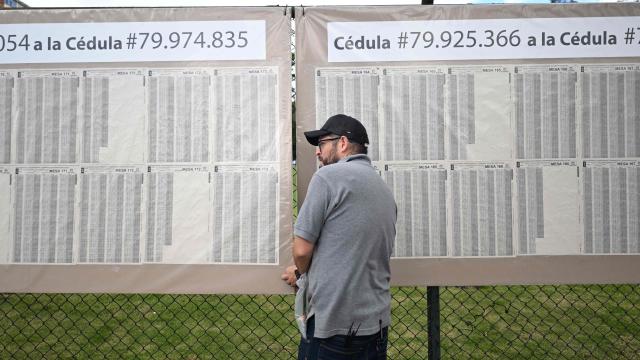 A man sets up an electoral roll outside a polling center in Bogota, on June 20, 2026, ahead of the presidential runoff election. Colombians vote on June 21, 2026 in a presidential runoff pitting a hard-right opera-singer-turned-lawyer against a leftist senator, an election with stark consequences for the country's stumbling peace process with armed groups and strained ties with Washington. (Photo by Luis ACOSTA / AFP)