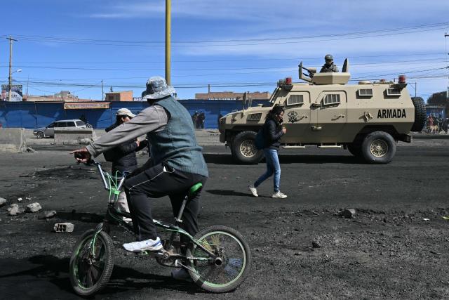 Residents remain near a military armoured vehicle at a blockade zone in Cruce Ventilla in El Alto, Bolivia on June 20, 2026, after Bolivian President Rodrigo Paz declared state of emergency. Bolivian President Rodrigo Paz declared a state of emergency across the Latin American country after more than six weeks of road blockades and protests demanding his resignation, saying he had exhausted "all avenues of dialogue." (Photo by AIZAR RALDES / AFP)
