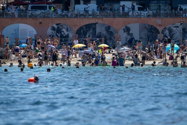 People take a sunbath at the beach in Marseille, southern France on June 20, 2026 as the heatwave sweeps across France. France issued a red heatwave alert across more than a third of the country for June 21, 2026 as a ferocious heatwave dug in and the government banned the consumption of alcohol during the annual Fete de la Musique festivities. (Photo by MIGUEL MEDINA / AFP)