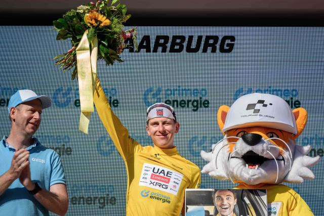 UAE Team Emirates-XRG's Slovenian rider Tadej Pogacar wearing the overall leader's yellow jersey celebrates on the podium of the fourth stage, a 23.7 km time trial from Aarburg to Aarburg, at the Men's Tour of Switzerland (Tour de Suisse) cycling race in Aarburg, Switzerland, on June 20, 2026. (Photo by Fabrice COFFRINI / AFP)