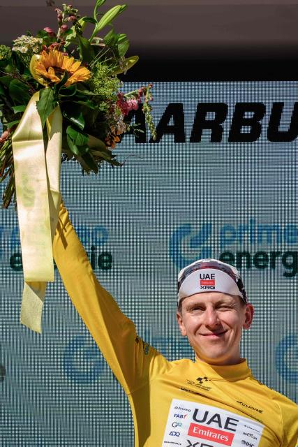 UAE Team Emirates-XRG's Slovenian rider Tadej Pogacar wearing the overall leader's yellow jersey celebrates on the podium of the fourth stage, a 23.7 km time trial from Aarburg to Aarburg, at the Men's Tour of Switzerland (Tour de Suisse) cycling race in Aarburg, Switzerland, on June 20, 2026. (Photo by Fabrice COFFRINI / AFP)