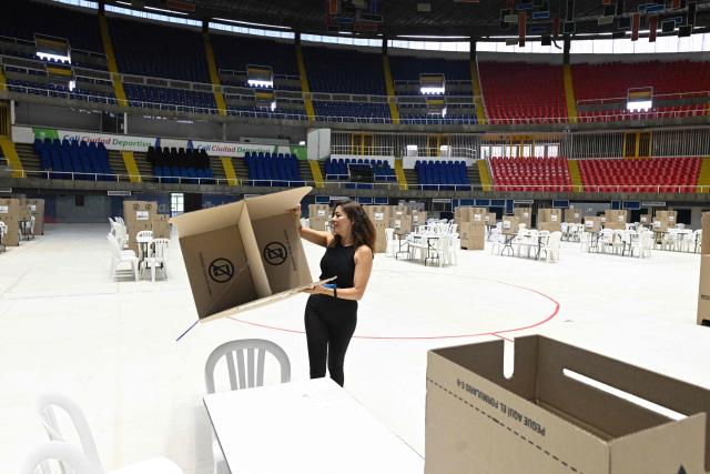 A woman arranges a polling station at a polling center in Cali, Colombia on June 20, 2026, the day before the presidential runoff election. Colombians vote on June 21, 2026 in a presidential runoff pitting a hard-right opera-singer-turned-lawyer against a leftist senator, an election with stark consequences for the country's stumbling peace process with armed groups and strained ties with Washington. (Photo by Joaquin SARMIENTO / AFP)