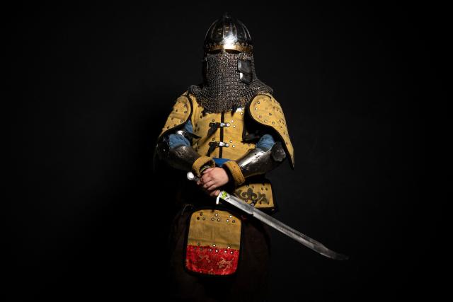 A competitor poses in his combat gear as part of the Knights of the Cage, a gala of the medieval armored combat or buhurt, in Onet-le-Chateau, southwestern France, on June 20, 2026. Fighters in armor with shields and swords, or axes, have taken part in about twenty fights in an MMA cage in Aveyron. It was overwhelmingly men who fought in individual "behourd profight" clashes, presented as the modern version of "what was the equivalent of MMA of the Middle Ages" by the town hall of Onet-le-Chateau. French, Polish, and British fighters participated in this event at the Salle d'Armes Ecole Ancienne (SAEA), a club specializing in buhurt.
"The word 'buhurt' comes from Old French; it was a recreational activity for men in the Middle Ages... It's the intersection of history and combat sports," explains Clement Carsac, president of SAEA Aveyron. 
Before the fights, participants must be weighed because, as in boxing, there are weight categories in buhurt profight. They then put on their armor and helmets, which can weigh up to six kilos. The outfit is rather expensive: "A complete set costs between 3,000 and 4,000 euros," according to Clement Carsac. (Photo by Valentine CHAPUIS / AFP)
