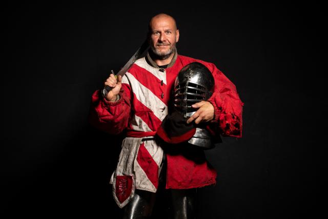 A competitor poses in his combat gear as part of the Knights of the Cage, a gala of the medieval armored combat or buhurt, in Onet-le-Chateau, southwestern France, on June 20, 2026. Fighters in armor with shields and swords, or axes, have taken part in about twenty fights in an MMA cage in Aveyron. It was overwhelmingly men who fought in individual "behourd profight" clashes, presented as the modern version of "what was the equivalent of MMA of the Middle Ages" by the town hall of Onet-le-Chateau. French, Polish, and British fighters participated in this event at the Salle d'Armes Ecole Ancienne (SAEA), a club specializing in buhurt.
"The word 'buhurt' comes from Old French; it was a recreational activity for men in the Middle Ages... It's the intersection of history and combat sports," explains Clement Carsac, president of SAEA Aveyron. 
Before the fights, participants must be weighed because, as in boxing, there are weight categories in buhurt profight. They then put on their armor and helmets, which can weigh up to six kilos. The outfit is rather expensive: "A complete set costs between 3,000 and 4,000 euros," according to Clement Carsac. (Photo by Valentine CHAPUIS / AFP)
