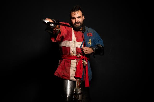 A competitor poses in his combat gear as part of the Knights of the Cage, a gala of the medieval armored combat or buhurt, in Onet-le-Chateau, southwestern France, on June 20, 2026. Fighters in armor with shields and swords, or axes, have taken part in about twenty fights in an MMA cage in Aveyron. It was overwhelmingly men who fought in individual "behourd profight" clashes, presented as the modern version of "what was the equivalent of MMA of the Middle Ages" by the town hall of Onet-le-Chateau. French, Polish, and British fighters participated in this event at the Salle d'Armes Ecole Ancienne (SAEA), a club specializing in buhurt.
"The word 'buhurt' comes from Old French; it was a recreational activity for men in the Middle Ages... It's the intersection of history and combat sports," explains Clement Carsac, president of SAEA Aveyron. 
Before the fights, participants must be weighed because, as in boxing, there are weight categories in buhurt profight. They then put on their armor and helmets, which can weigh up to six kilos. The outfit is rather expensive: "A complete set costs between 3,000 and 4,000 euros," according to Clement Carsac. (Photo by Valentine CHAPUIS / AFP)