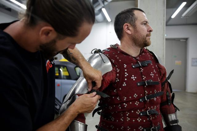 A competitor gets part of his armor repaired before fighting in an MMA (mixed martial arts) arena at the Knights of the Cage, a gala of the medieval armored combat or buhurt, in Onet-le-Chateau, southwestern France, on June 20, 2026. Fighters in armor with shields and swords, or axes, have taken part in about twenty fights in an MMA cage in Aveyron. It was overwhelmingly men who fought in individual "behourd profight" clashes, presented as the modern version of "what was the equivalent of MMA of the Middle Ages" by the town hall of Onet-le-Chateau. French, Polish, and British fighters participated in this event at the Salle d'Armes Ecole Ancienne (SAEA), a club specializing in buhurt.
"The word 'buhurt' comes from Old French; it was a recreational activity for men in the Middle Ages... It's the intersection of history and combat sports," explains Clement Carsac, president of SAEA Aveyron. 
Before the fights, participants must be weighed because, as in boxing, there are weight categories in buhurt profight. They then put on their armor and helmets, which can weigh up to six kilos. The outfit is rather expensive: "A complete set costs between 3,000 and 4,000 euros," according to Clement Carsac. (Photo by Valentine CHAPUIS / AFP)