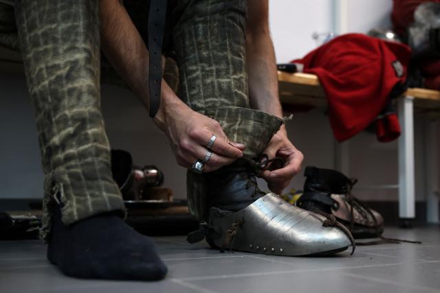 A competitor prepares his armor before fighting in an MMA (mixed martial arts) arena at the Knights of the Cage, a gala of the medieval armored combat or buhurt, in Onet-le-Chateau, southwestern France, on June 20, 2026. Fighters in armor with shields and swords, or axes, have taken part in about twenty fights in an MMA cage in Aveyron. It was overwhelmingly men who fought in individual "behourd profight" clashes, presented as the modern version of "what was the equivalent of MMA of the Middle Ages" by the town hall of Onet-le-Chateau. French, Polish, and British fighters participated in this event at the Salle d'Armes Ecole Ancienne (SAEA), a club specializing in buhurt.
"The word 'buhurt' comes from Old French; it was a recreational activity for men in the Middle Ages... It's the intersection of history and combat sports," explains Clement Carsac, president of SAEA Aveyron. 
Before the fights, participants must be weighed because, as in boxing, there are weight categories in buhurt profight. They then put on their armor and helmets, which can weigh up to six kilos. The outfit is rather expensive: "A complete set costs between 3,000 and 4,000 euros," according to Clement Carsac. (Photo by Valentine CHAPUIS / AFP)