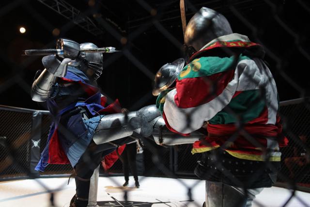 Competitors fight in an MMA (mixed martial arts) arena during the Knights of the Cage, a gala of a medieval armored combat or buhurt, in Onet-le-Chateau, southwestern France, on June 20, 2026. Fighters in armor with shields and swords, or axes, have taken part in about twenty fights in an MMA cage in Aveyron. It was overwhelmingly men who fought in individual "behourd profight" clashes, presented as the modern version of "what was the equivalent of MMA of the Middle Ages" by the town hall of Onet-le-Chateau. French, Polish, and British fighters participated in this event at the Salle d'Armes Ecole Ancienne (SAEA), a club specializing in buhurt.
"The word 'buhurt' comes from Old French; it was a recreational activity for men in the Middle Ages... It's the intersection of history and combat sports," explains Clement Carsac, president of SAEA Aveyron. 
Before the fights, participants must be weighed because, as in boxing, there are weight categories in buhurt profight. They then put on their armor and helmets, which can weigh up to six kilos. The outfit is rather expensive: "A complete set costs between 3,000 and 4,000 euros," according to Clement Carsac. (Photo by Valentine CHAPUIS / AFP)