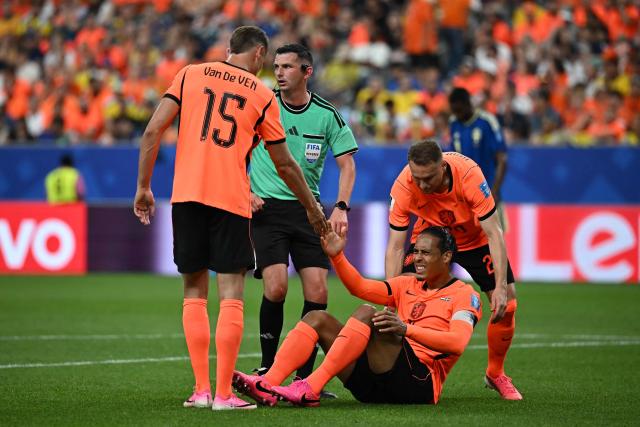 Netherlands' defender #04 Virgil van Dijk (C) is helped up by Netherlands' defender #15 Micky Van de Ven (L) and Netherlands' midfielder #20 Teun Koopmeiners (R)  during the 2026 World Cup Group F football match between the Netherlands and Sweden at the Houston Stadium in Houston on June 20, 2026.  (Photo by Paul ELLIS / AFP)